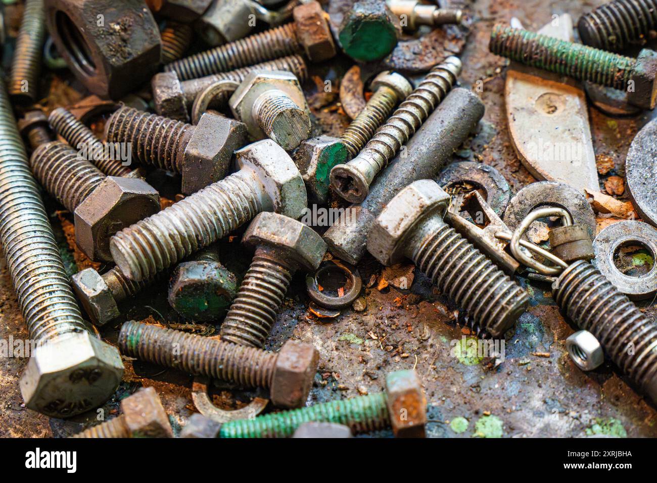Metallwerkstatt mit verschiedenen Schrauben, Bolzen und Muttern auf einer Werkbank, die mit Schmutz und Werkzeugresten bedeckt ist Stockfoto