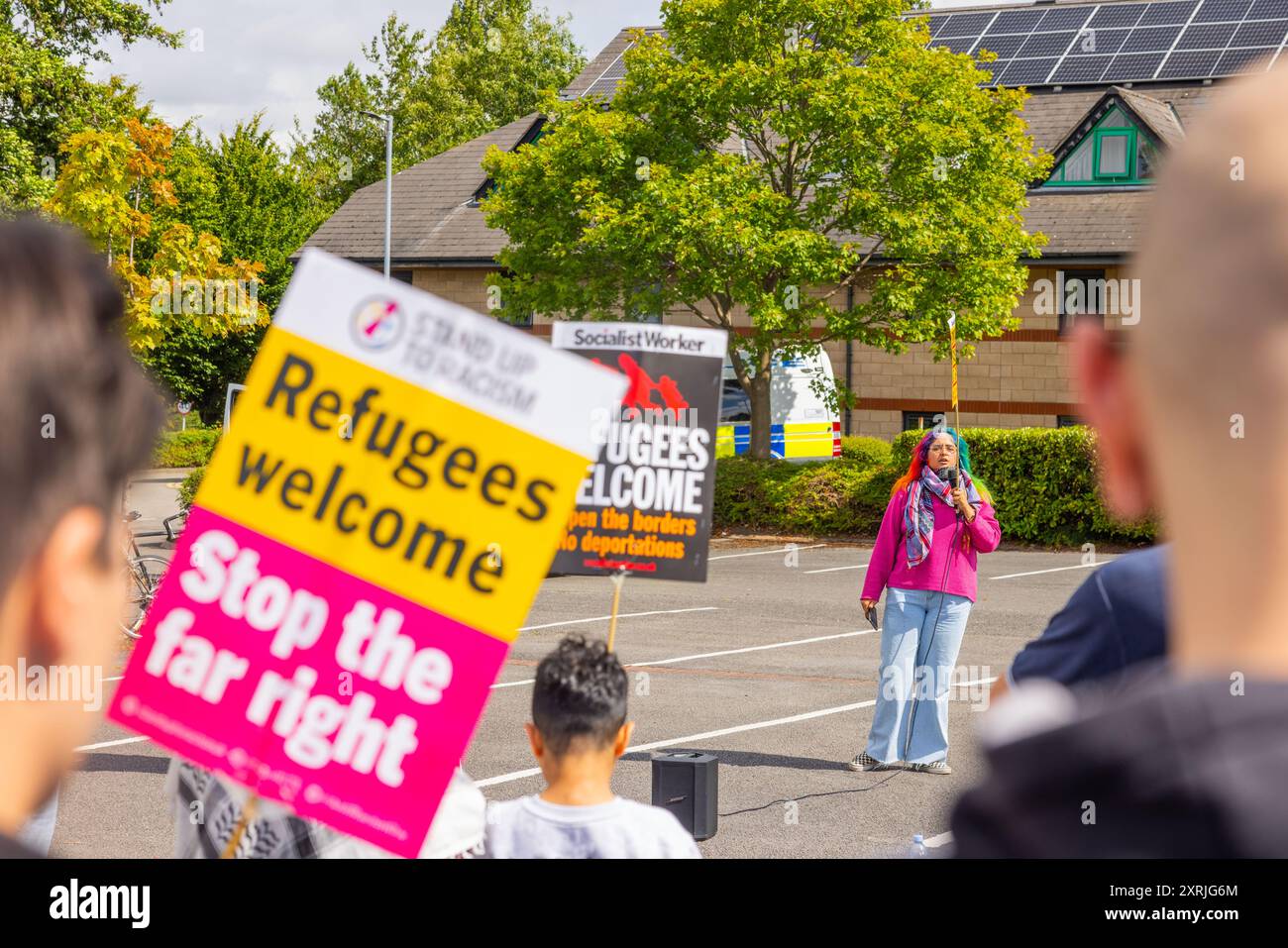 Wakefield, Großbritannien. AUGUST 2024. Lady hält eine Rede neben dem Willkommensschild für Flüchtlinge, während sich über hundert Gegendemonstratoren vor dem Cedar Court Hotel versammelten, um auf einen rechten Mob aufgrund der Rolle des Hotels bei der Unterbringung von Migranten zu warnen. Die Gegendemonstratoren waren aus SUTR und anderen linksgerichteten Gruppen und hielten Reden. Die Polizeipräsenz war mit 20 Lieferwagen und 2 gepanzerten „Bearcat“-Fahrzeugen außergewöhnlich hoch. Keine Demonstranten im rechten Flügel kamen an und die Gegendemo ging ohne Probleme weg. Credit Milo Chandler/Alamy Live News Stockfoto