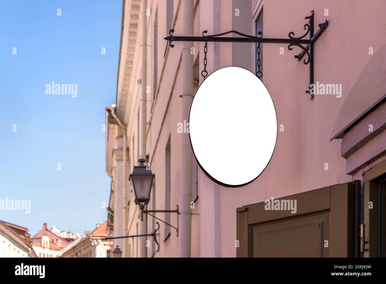 Weißes Modell Des Ladenschilds, Das An Der Rosafarbenen Wand Hängt. Leeres ovales Ladenschild für das Logo Stockfoto
