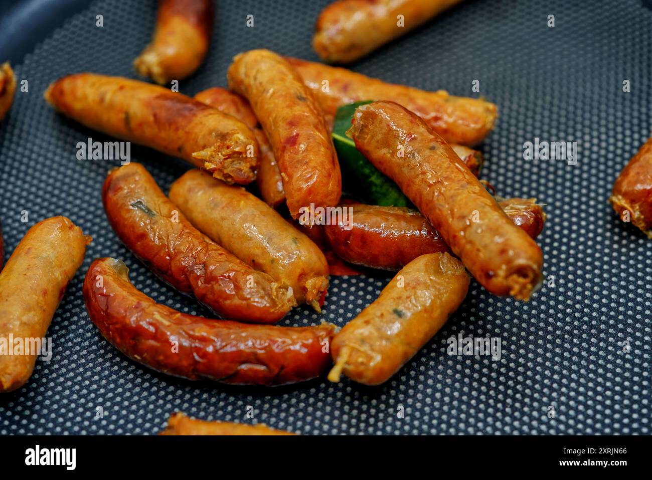 Sai Oua, die traditionelle thailändische Nördliche Wurst, die kleine Art von Sai Oua auf schwarzem Pfannenbraten, Haufen von thailändischen Nördlichen Würstchen, Nahaufnahme Lebensmittelbild Stockfoto