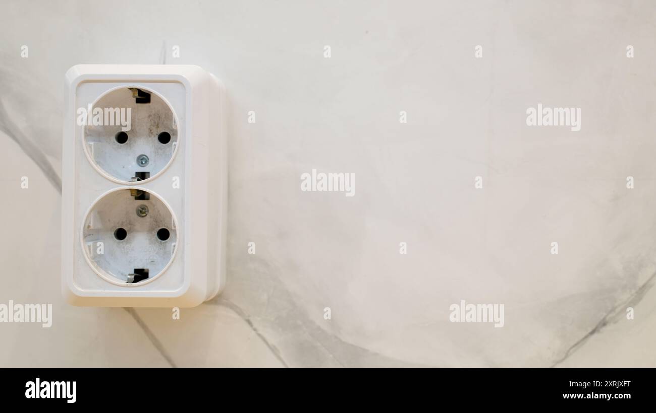 Nahaufnahme einer weißen doppelten Steckdose an einer einfachen Wand. Europäische Buchse mit Rundlöchern für Stecker Stockfoto