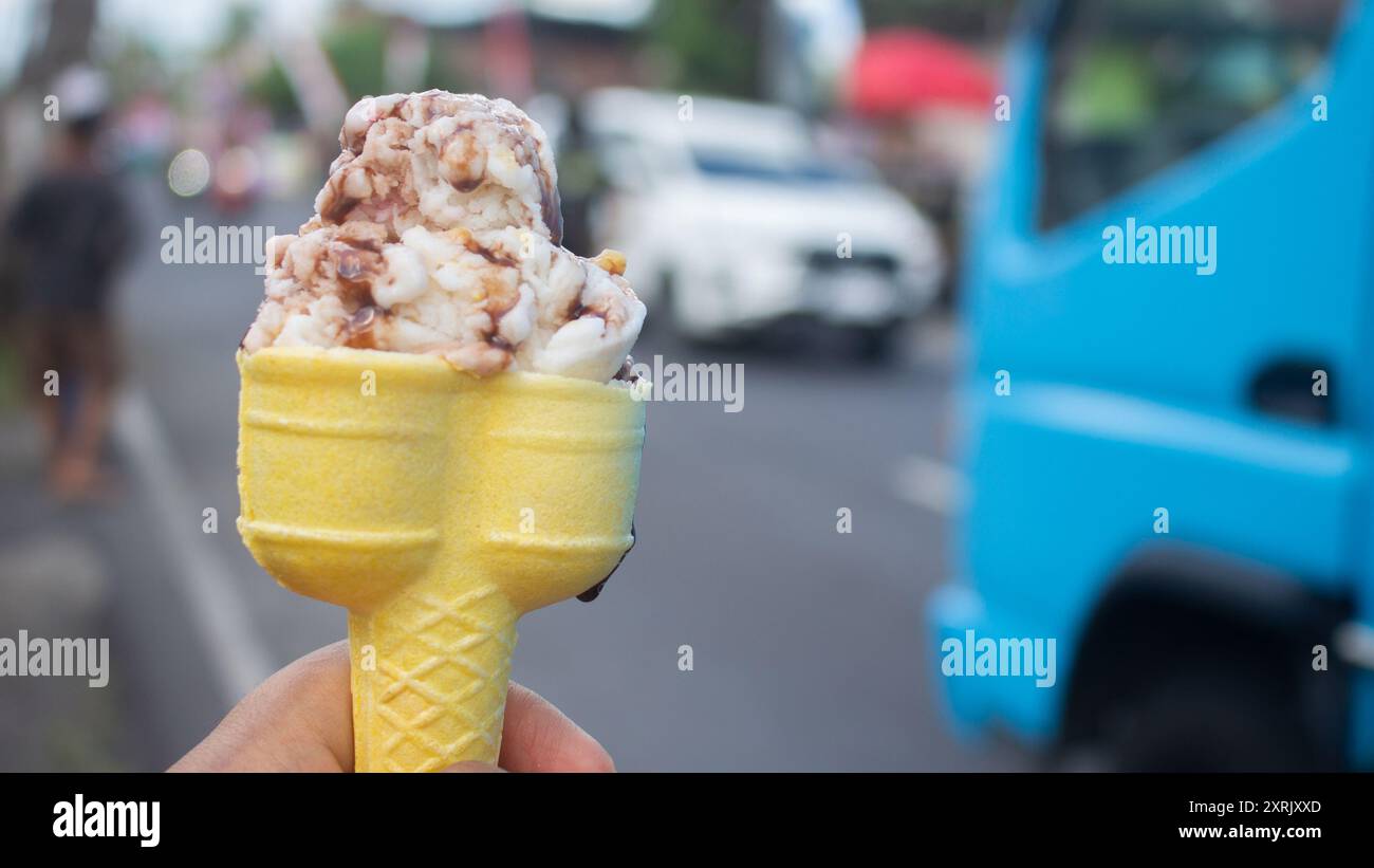 Halten Sie an heißen Sommertagen ein weiches Eis in der Hand vor der geschäftigen Kulisse der Straße. Stockfoto