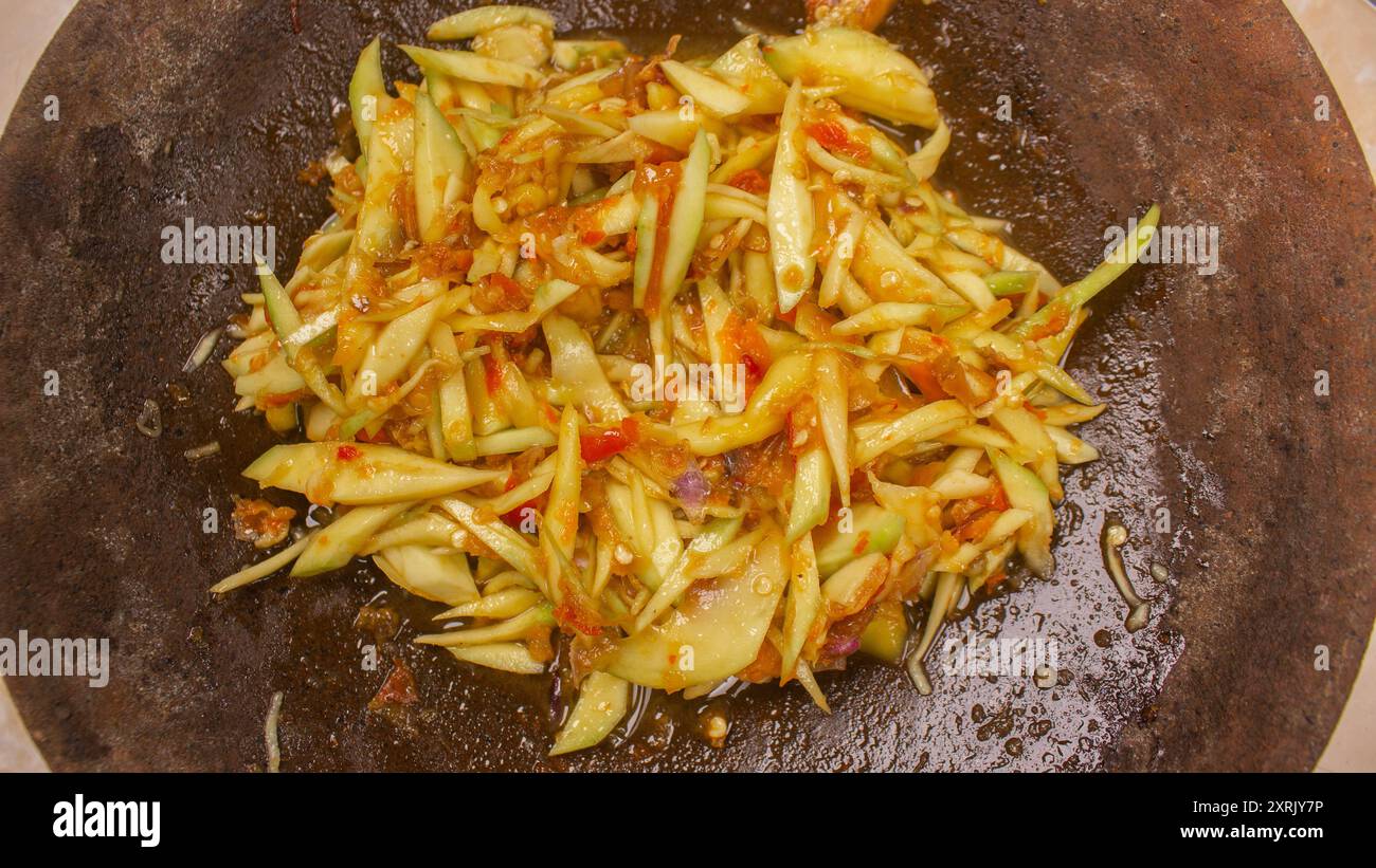 Sambal Mangga oder Chili Sauce gemischt mit geschnittenen jungen Manggofrüchten servieren Sie auf traditionellem Mörtel und Stößel . Authentisch typisch für indonesische scharfe Chili Stockfoto