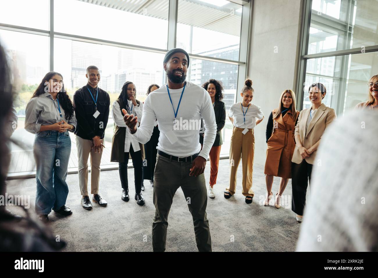 Selbstbewusster Geschäftsmann, der in einer modernen Büroumgebung mit einem vielfältigen Team eine ansprechende Teambuilding-Sitzung leitet und die Kommunikation und Zusammenarbeit fördert Stockfoto