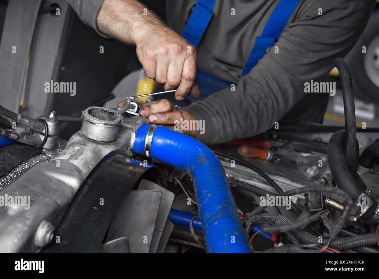 Ein Mechaniker stellt die Motorkomponenten in einer gut ausgestatteten Garage sorgfältig mit einem Schraubenschlüssel ein. Der Schwerpunkt liegt auf den komplizierten Details der Maschinen und den geschickten Händen bei der Arbeit, die einen Moment der Fahrzeugwartung veranschaulichen. Stockfoto