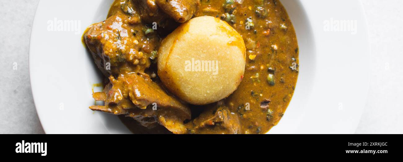 Blick von oben auf nigerianische Ogbono-Suppe und eba auf einem weißen ...