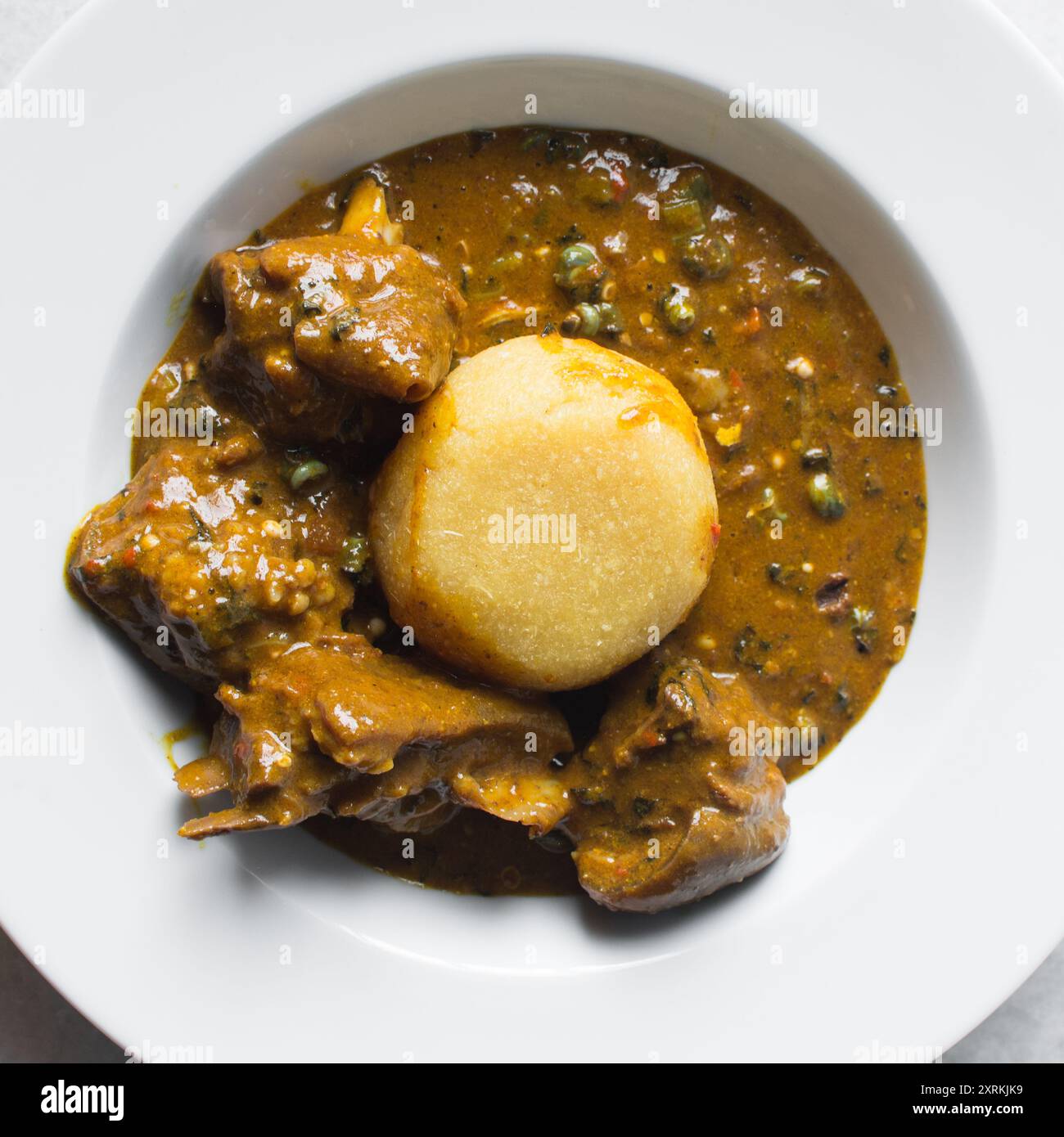 Blick von oben auf nigerianische Ogbono-Suppe und eba auf einem weißen ...