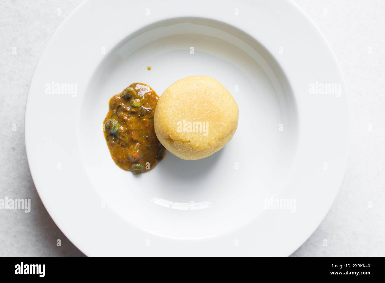 Blick von oben auf nigerianische Ogbono-Suppe und eba auf einem weißen Teller, Blick von oben auf Ogbono-Suppe mit garri und verschiedenen Fleischsorten auf einem Suppenteller Stockfoto