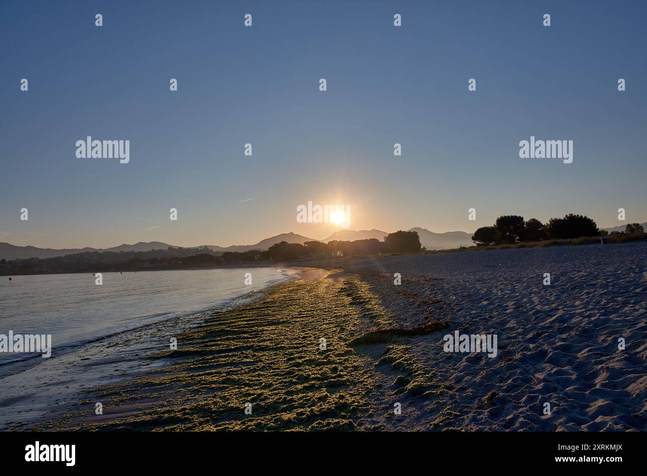 Die atemberaubende Schönheit der Playa de la Ladeira in Baiona bei Sonnenaufgang. Wenn die Sonne aufgeht, taucht ihr goldenes Licht den Sandstrand und das ruhige Wasser und schafft so Stockfoto