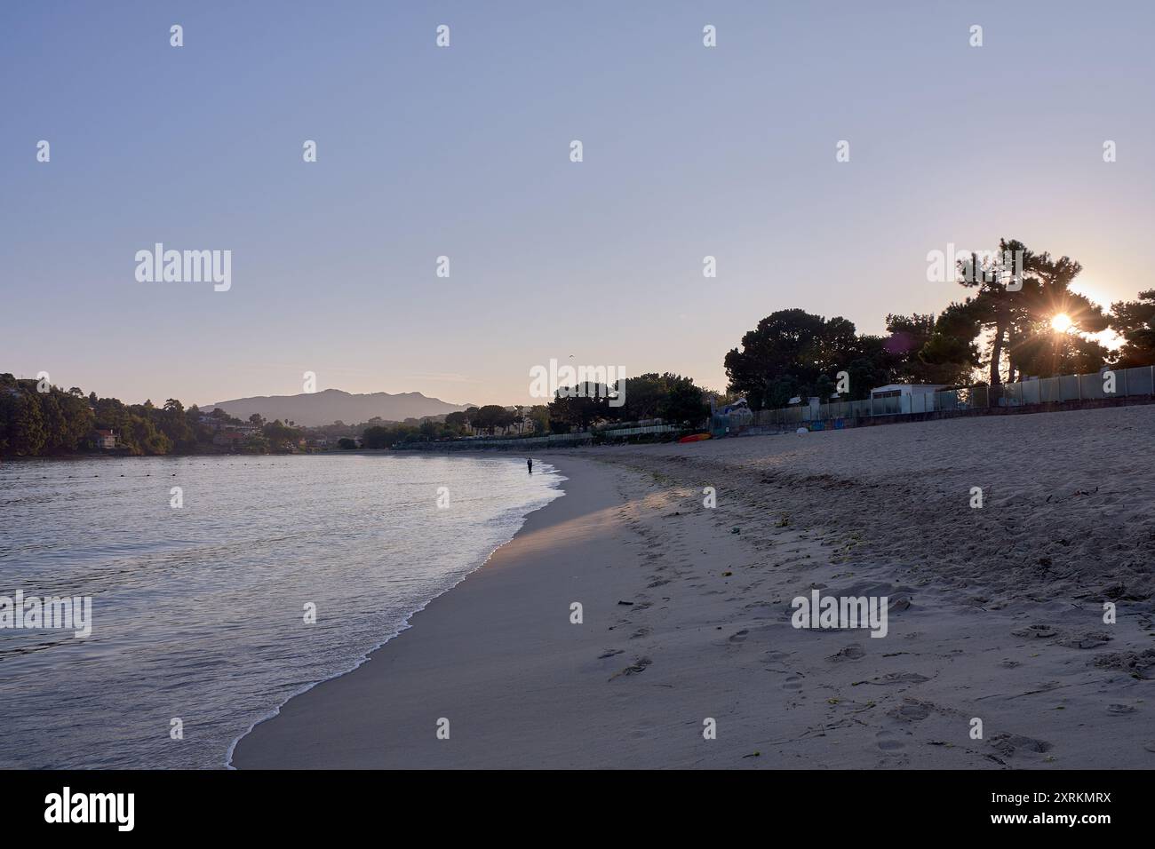 Die atemberaubende Schönheit der Playa de la Ladeira in Baiona bei Sonnenaufgang. Wenn die Sonne aufgeht, taucht ihr goldenes Licht den Sandstrand und das ruhige Wasser und schafft so Stockfoto