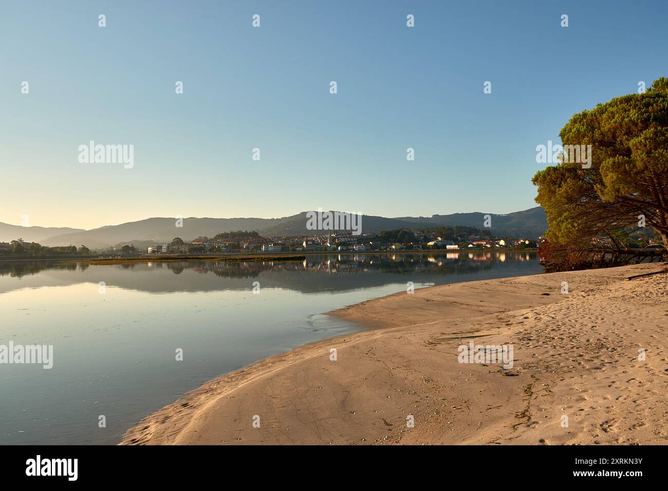 Die atemberaubende Schönheit der Playa de la Ladeira in Baiona bei Sonnenaufgang. Wenn die Sonne aufgeht, taucht ihr goldenes Licht den Sandstrand und das ruhige Wasser und schafft so Stockfoto
