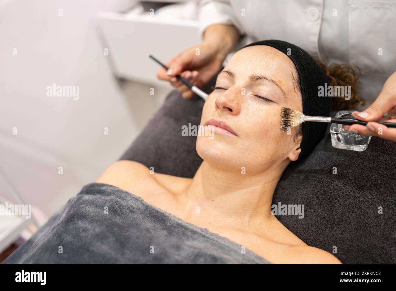 Pflanzenpflegekraft, die Reinigungsöl auf den Kunden im Schönheitszentrum aufträgt Stockfoto