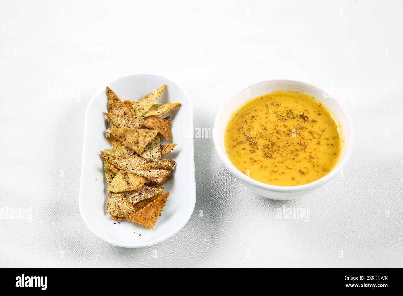 Kürbis-Karotten-Suppe mit Sahne und Pita-Brotchips auf weißem Hintergrund. Bokeh-Shot. Stockfoto