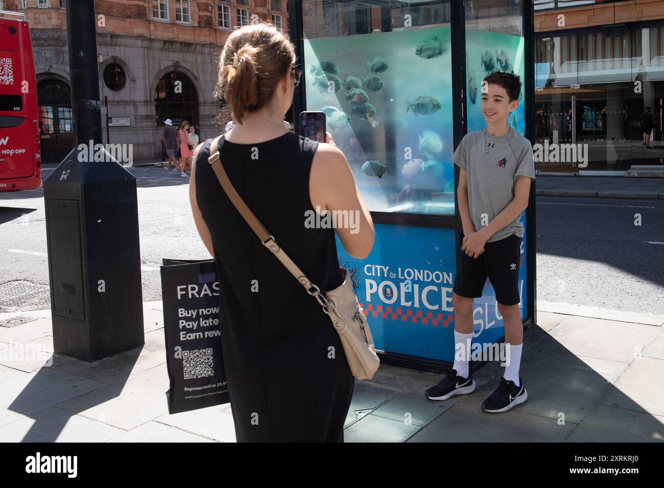 London, Großbritannien. August 2024. Am Sonntag, den 11. August 2024, machen die Leute Fotos von dem siebten neuen Kunstwerk des Street-Künstlers Banksy, das Piranha-Fische auf einer Polizeiwache in Ludgate Hill, City of London, London, England, zeigt. Foto: Justin ng/Alamy Live News Stockfoto