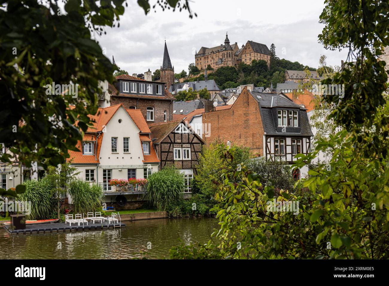 Marburg, Deutschland. August 2024. Die Burg Marburg, auch Landgrafenburg Marburg genannt, erhebt sich über der Stadt. Blick vom Ufer der Lahn über Häuser im südlichen Viertel bis zur Altstadt (Oberstadt). Sie entstand im 11. Jahrhundert als Burg und wurde im 13. Jahrhundert von den Landgrafen von Hessen in ein Wohnschloss umgewandelt. Seit 1981 beherbergt das Schloss das Kunstgeschichtliche Museum der Philipps-Universität Marburg. Quelle: Christian Lademann/dpa/Alamy Live News Stockfoto