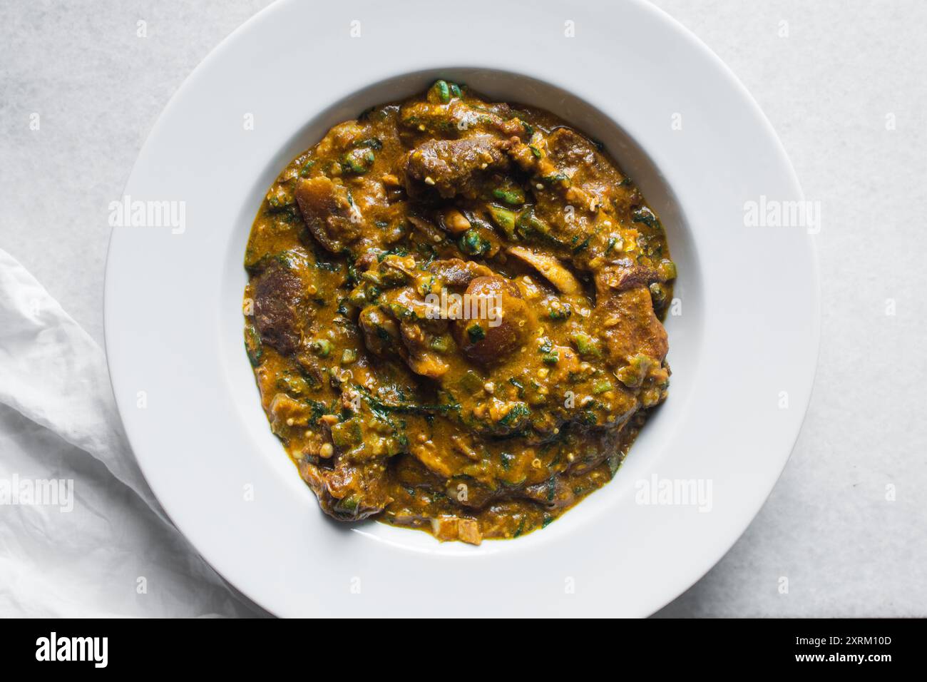 Blick von oben auf die nigerianische Ogbono-Suppe auf einem weißen ...