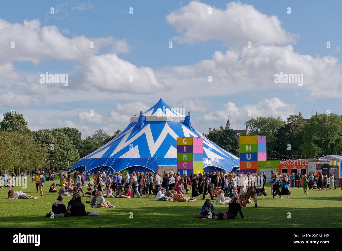 Leute sitzen in einem Park und haben Spaß an einem Circus-Zelt und an der Kasse für das Fringe Festival in Edinburgh Schottland. August 2024 Stockfoto