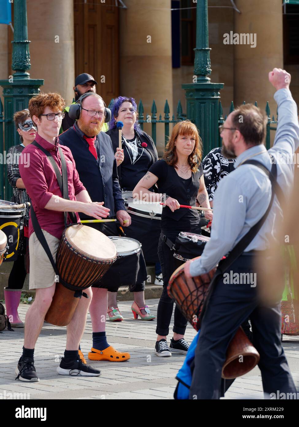 Eine eklektische Gruppe von Leuten spielt Schlagzeug mit einem Dirigenten während des Fringe Festivals in Edinburgh Schottland. August 2024 Stockfoto