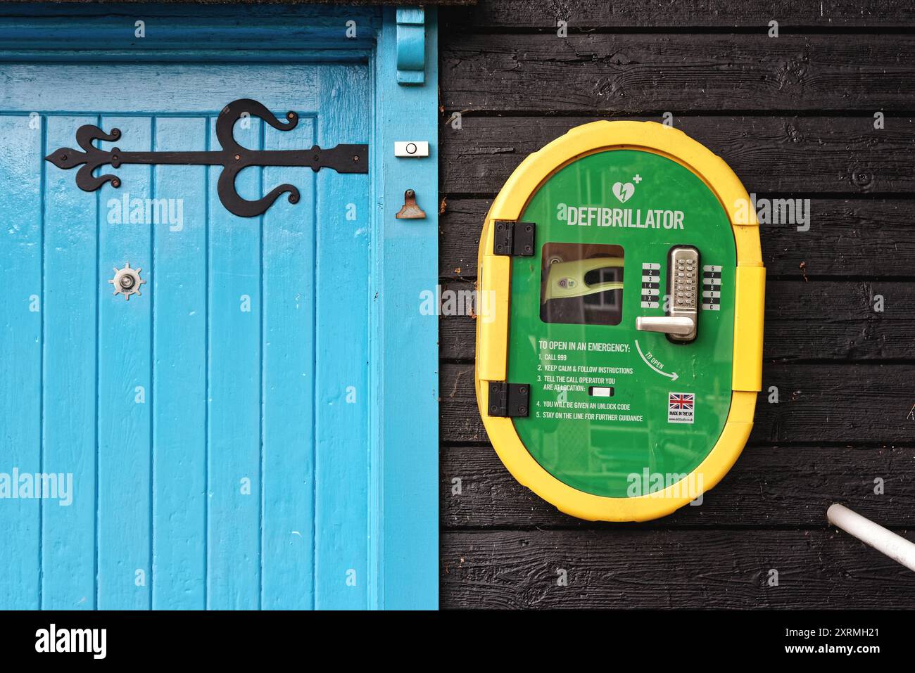 Ein Defibrillator für die öffentliche Verwendung, der an einer Holzwand eines Gebäudes in Byfleet Surrey England (Großbritannien) angebracht ist Stockfoto