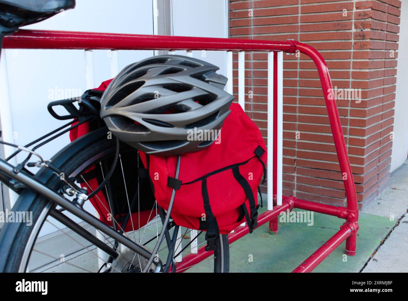 Ein Fahrradhelm, der an einem Fahrrad mit Tourentaschen auf einem Fahrradständer in der Innenstadt befestigt ist. Stockfoto