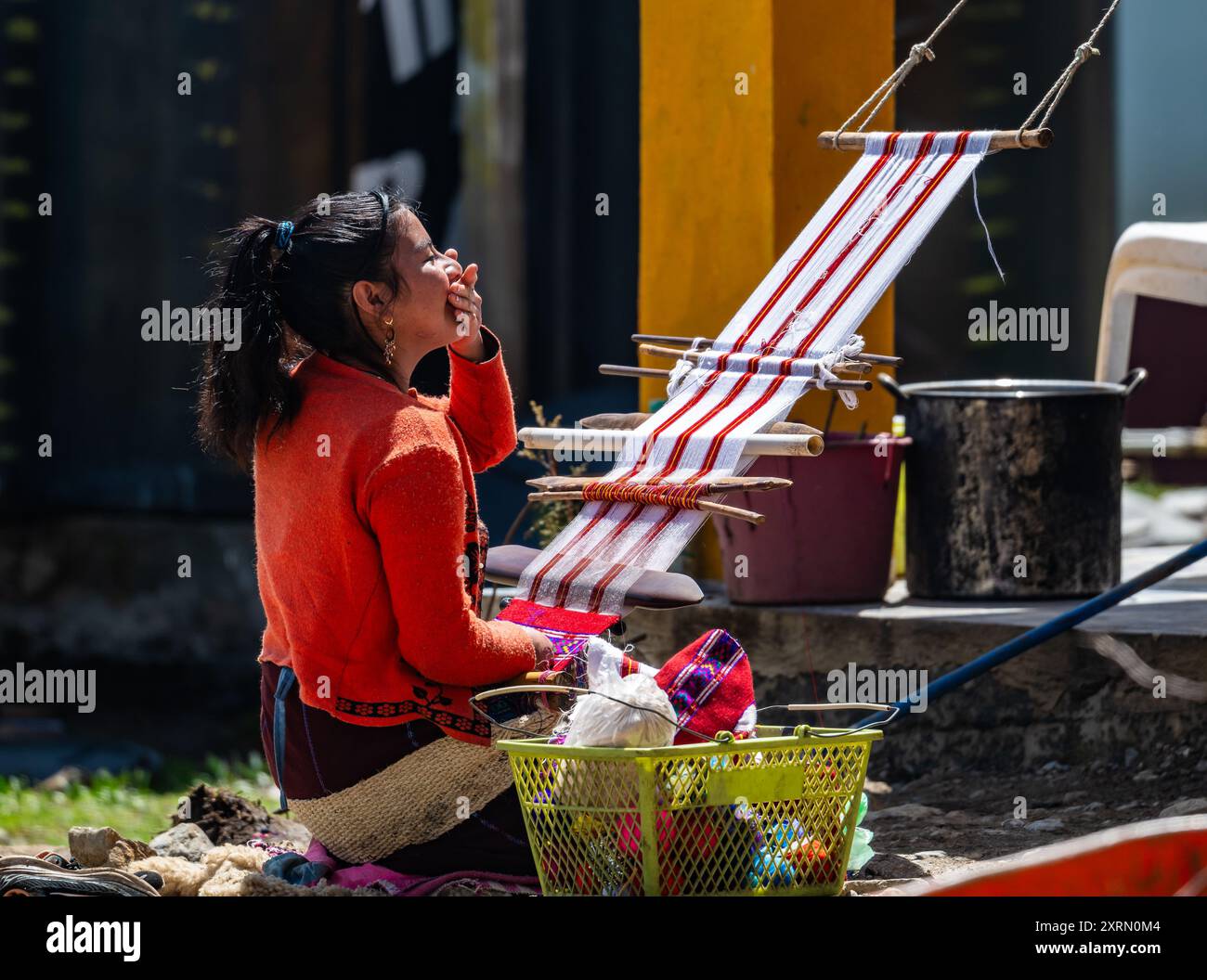 Eine junge indigene Maya-Frau, die auf traditionelle Weise handgewebte Tuch mit Rückenriemen Webstuhl webt. Guatemala. Stockfoto