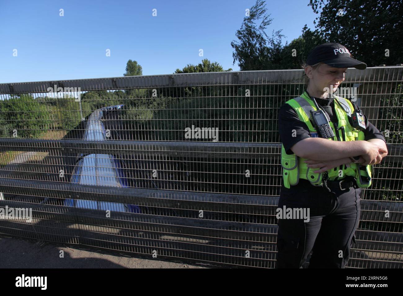 Selby, England, Großbritannien. August 2024. Ein Polizist wacht auf der Brücke, während ein Drax-Zug mit Treibstoff darunter vorbeifährt. Demonstranten argumentieren, dass die Holzgranulat, die Drax Power Station Burns verursacht, Wälder, Tiere und Gemeinden auf der ganzen Welt schadet. Die Demonstranten fordern, dass das Kraftwerk Drax geschlossen wird und dass die neue Labour-Regierung die umweltschädliche Biomasseindustrie beendet. Quelle: ZUMA Press, Inc./Alamy Live News Stockfoto