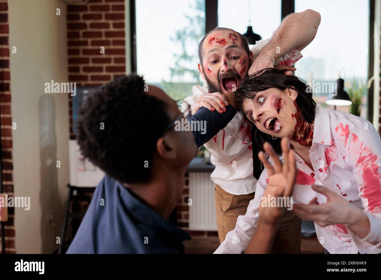 Schauspieler, die Zombies in der Horrorfilmszene spielen und Geschäftsmann in den Arm beißen, um Fleisch zu essen. Mann und Frau mit finsteren Monstern Rollen in Thriller-Slasher-Film, die menschliches Fleisch auf dem Büroset verzehren Stockfoto