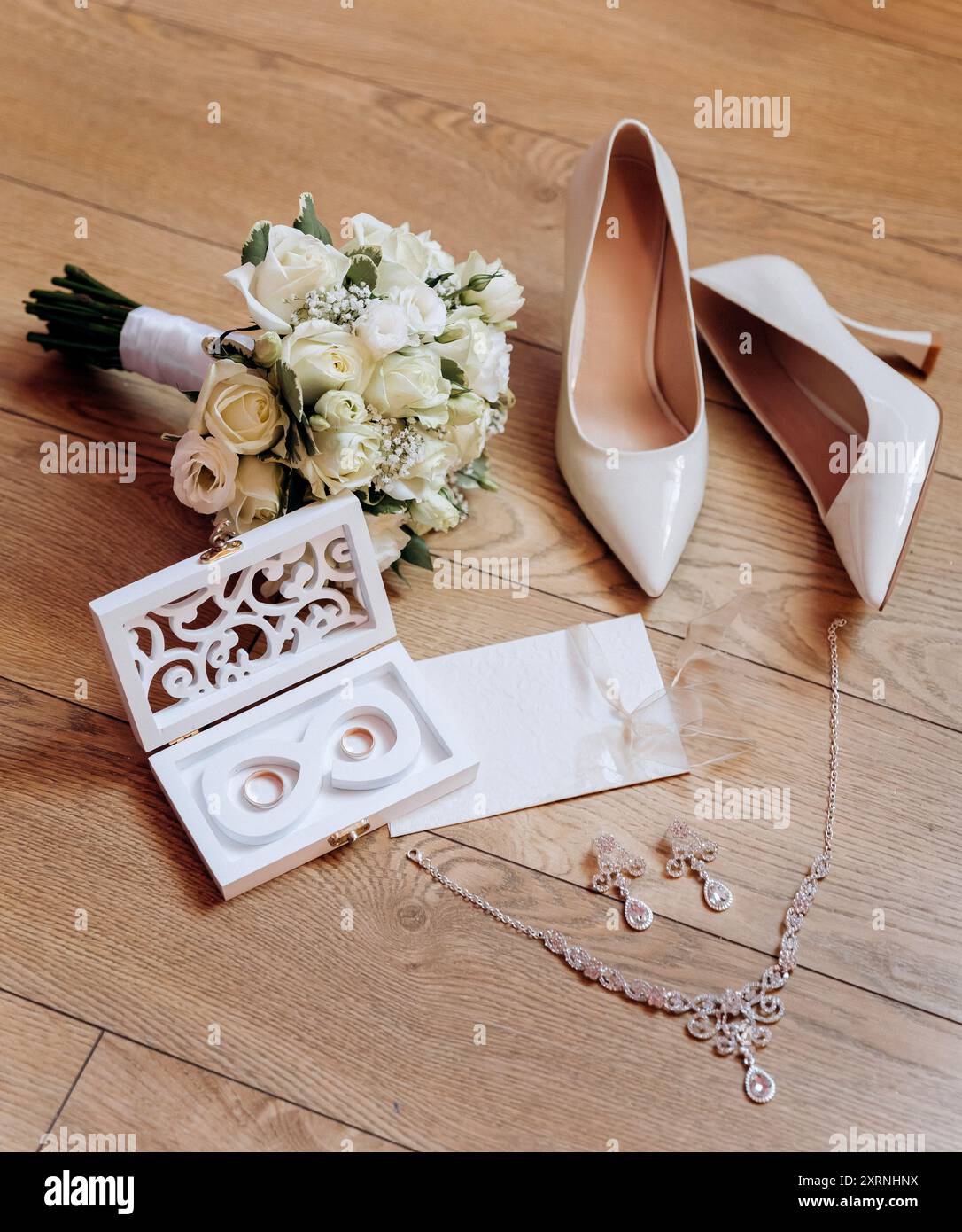 Brautjungfernkostüme: Absatzschuhe, Blumenstrauß, Ringe, Parfüm und Einladung auf dem Tisch Stockfoto