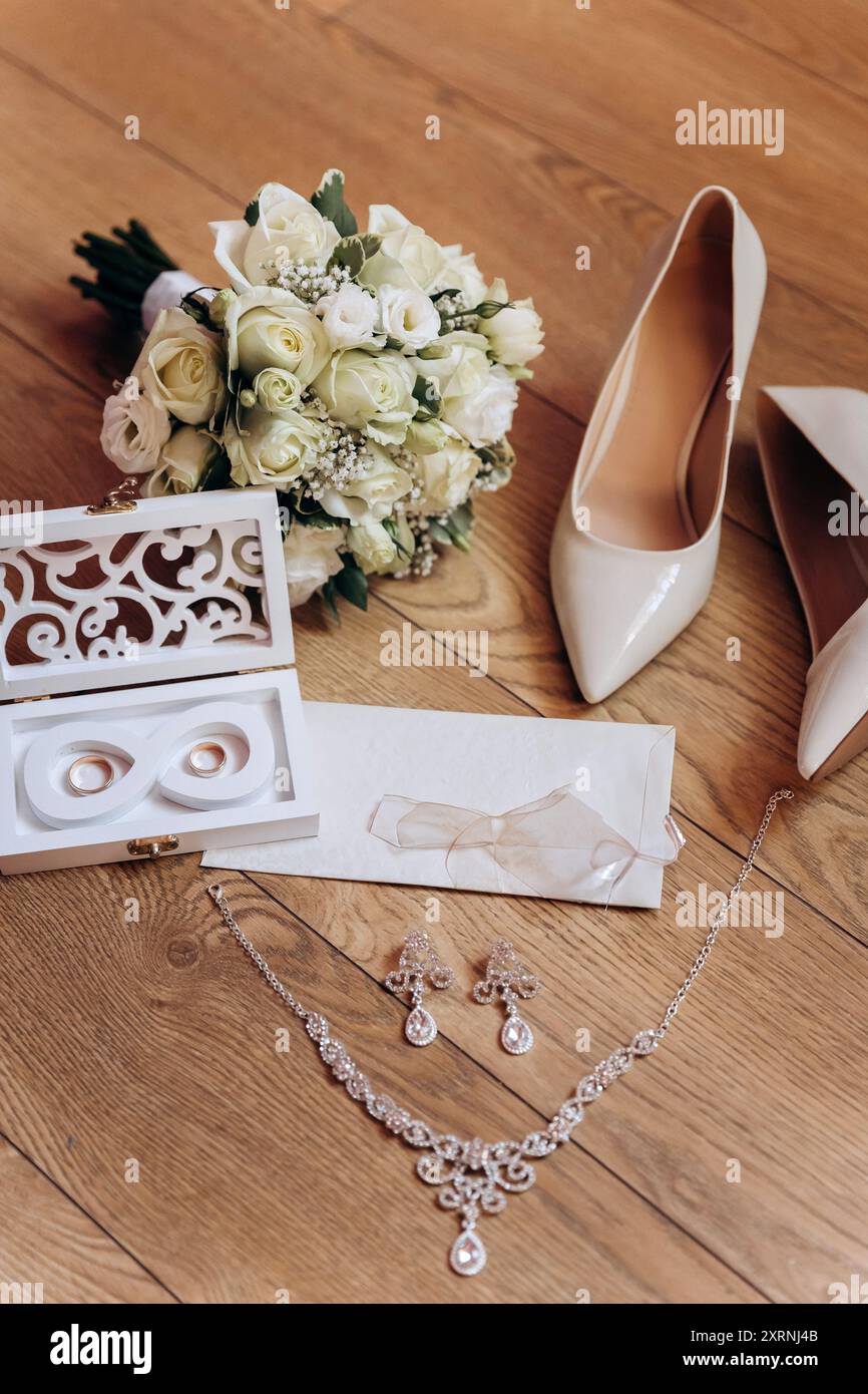 Brautjungfernkostüme: Absatzschuhe, Blumenstrauß, Ringe, Parfüm und Einladung auf dem Tisch Stockfoto