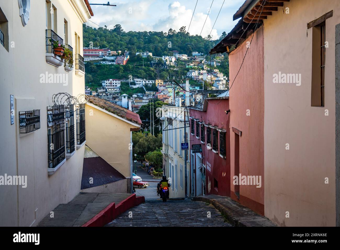 Bunt bemalte Wohngebäude entlang einer engen Gasse. Quetzaltenango, Guatemala. Stockfoto