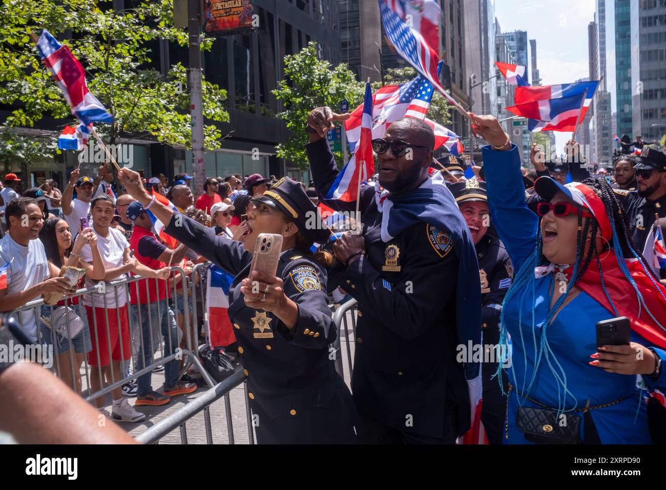 NEW YORK, NEW YORK – 11. AUGUST: Beamte des New York Police Department (NYPD) interagieren mit Zuschauern bei der Dominican Day Parade auf der 6th Avenue am 11. August 2024 in New York City. Die National Dominican Day Parade feierte 42 Jahre Marsch auf der Sixth Avenue in Manhattan. Die Parade feiert dominikanische Kultur, Folklore und Traditionen. Stockfoto