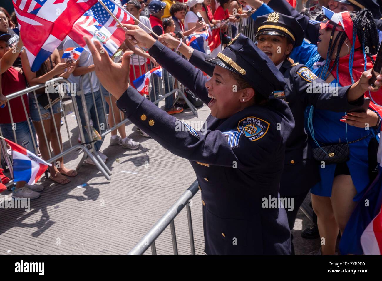 NEW YORK, NEW YORK – 11. AUGUST: Beamte des New York Police Department (NYPD) interagieren mit Zuschauern bei der Dominican Day Parade auf der 6th Avenue am 11. August 2024 in New York City. Die National Dominican Day Parade feierte 42 Jahre Marsch auf der Sixth Avenue in Manhattan. Die Parade feiert dominikanische Kultur, Folklore und Traditionen. Stockfoto