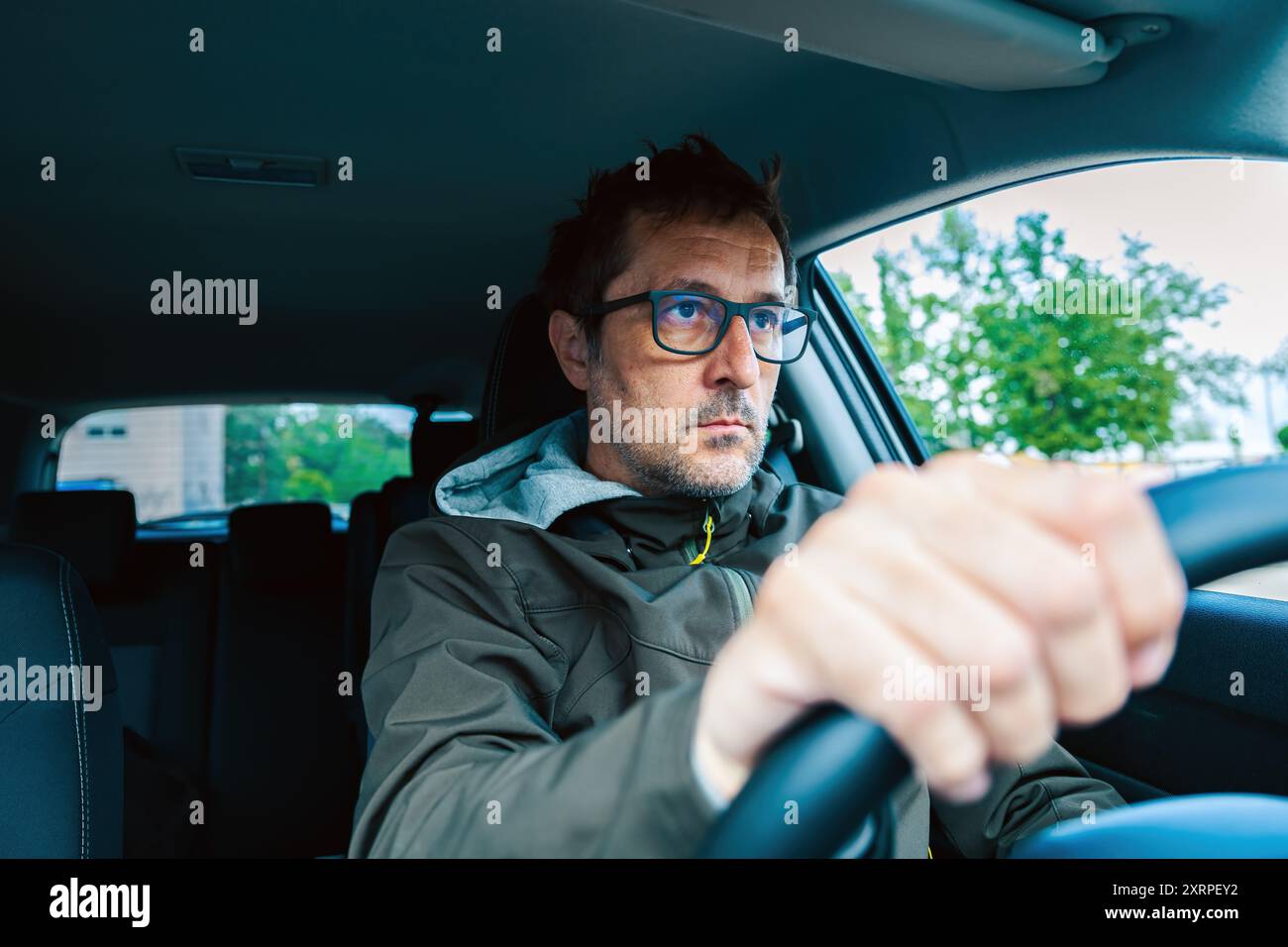 Vorsichtiger Fahrer mit einer Brille und Blick auf die Straße, die vor Ihnen liegt, während Sie das Fahrzeug fahren, selektiver Fokus Stockfoto