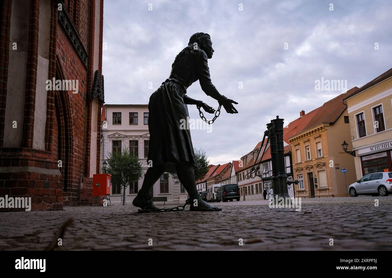 09. August 2024, Sachsen-Anhalt, Tangermünde: Eine Skulptur von Grete Linde steht auf dem Marktplatz neben dem Rathaus. Margarete von Minden, kurz Grete Minde, war eine verarmte Patriziertochter aus Tangermünde, die wegen angeblicher Brandstiftung hingerichtet wurde. Ihr Leben wurde Gegenstand mehrerer künstlerischer Arbeiten. Die bekannteste ist Fontanes Grete Minde. Foto: Jens Kalaene/dpa Stockfoto