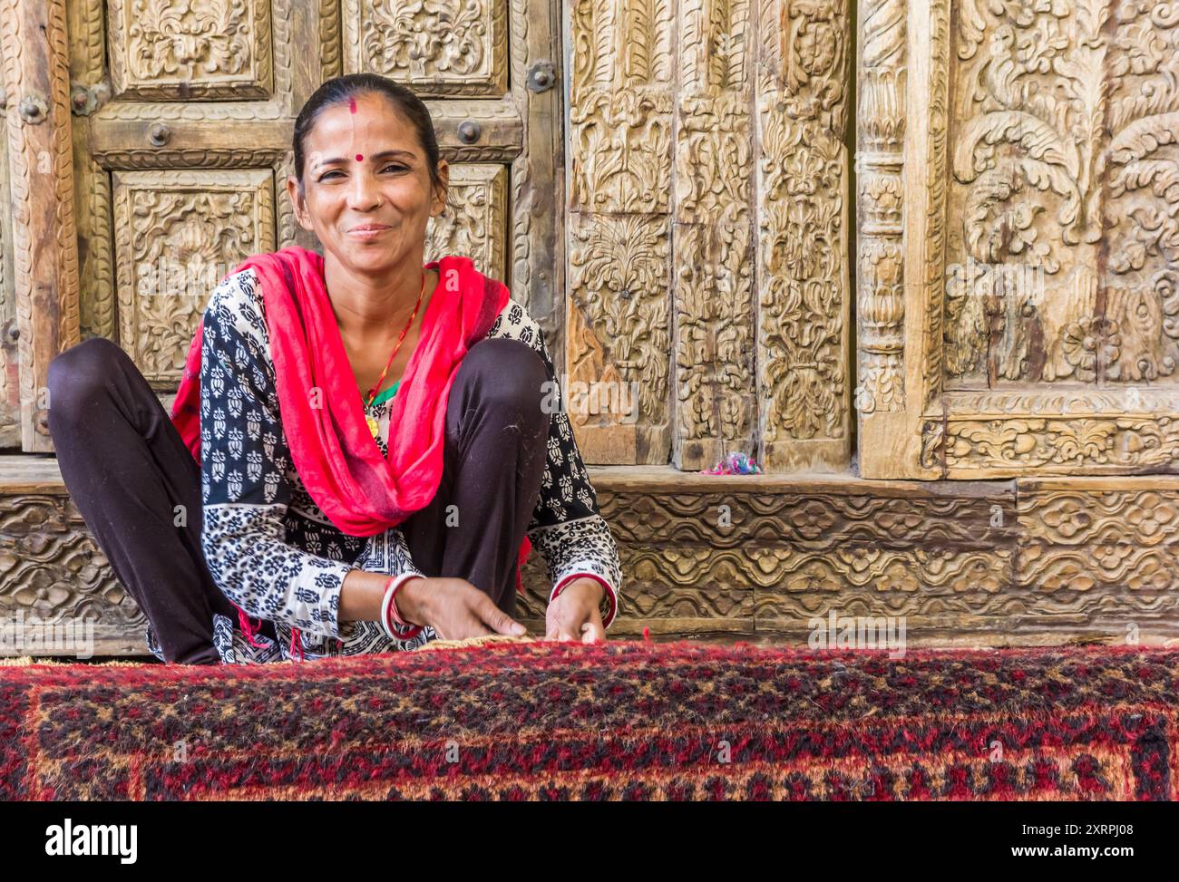 Lächelnde Indianerin arbeitet an einem handgefertigten Teppich in Jaipur, Indien Stockfoto