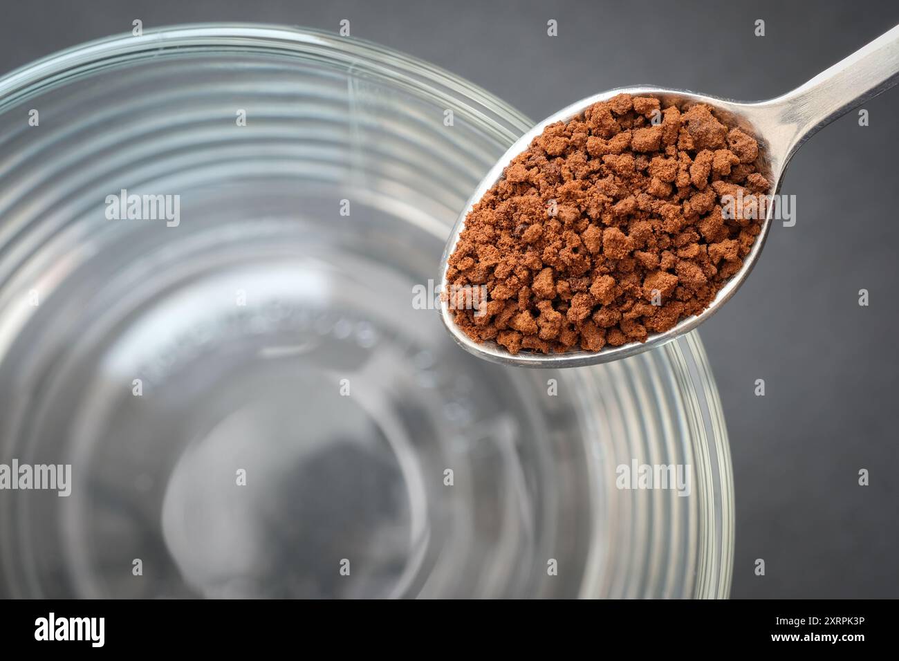 Instantkaffee auf Teelöffel mit Glas Kaffee Tasse Hintergrund. Stockfoto