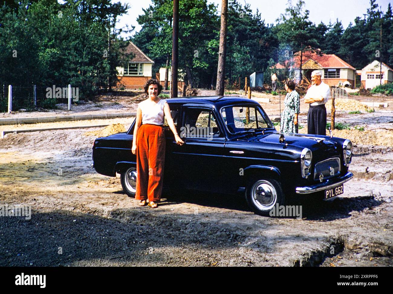 Lächelnde stolze Frau, Eigentümerin des Ford Prefect Car in der Gegend, die neue Wohnsiedlung in Vorstädten errichtet, Großbritannien 1956 Stockfoto