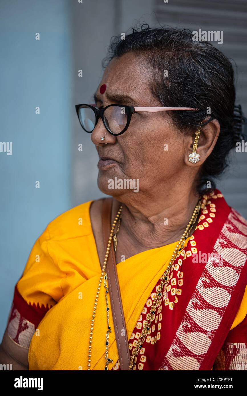 Indische alte Dame mit Brille und gelbem Saree. Südasiatische hinduistische religiöse ältere Frau in traditionellem Sari. Straßenfoto, Reise p Stockfoto