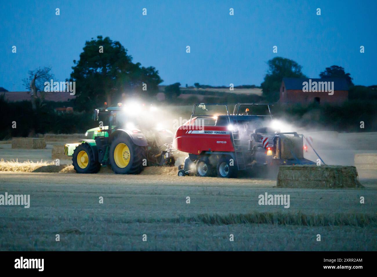 Die Bauern arbeiten bis spät in die Nacht, um die Ernte Anfang August zu ernten. Die Bauern verwenden leistungsstarke Lichter an ihren Traktoren, damit sie bis spät in den Abend ernten können. Die Farm befindet sich im ländlichen Warwickshire in den Midlands, Großbritannien. Stockfoto