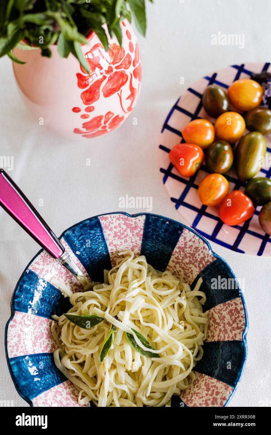 basilikum, Mini-Tomaten und große Schüssel frische Nudeln Stockfoto