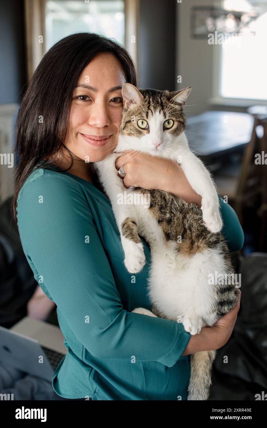 Frau umarmt Katze und lächelt Stockfoto