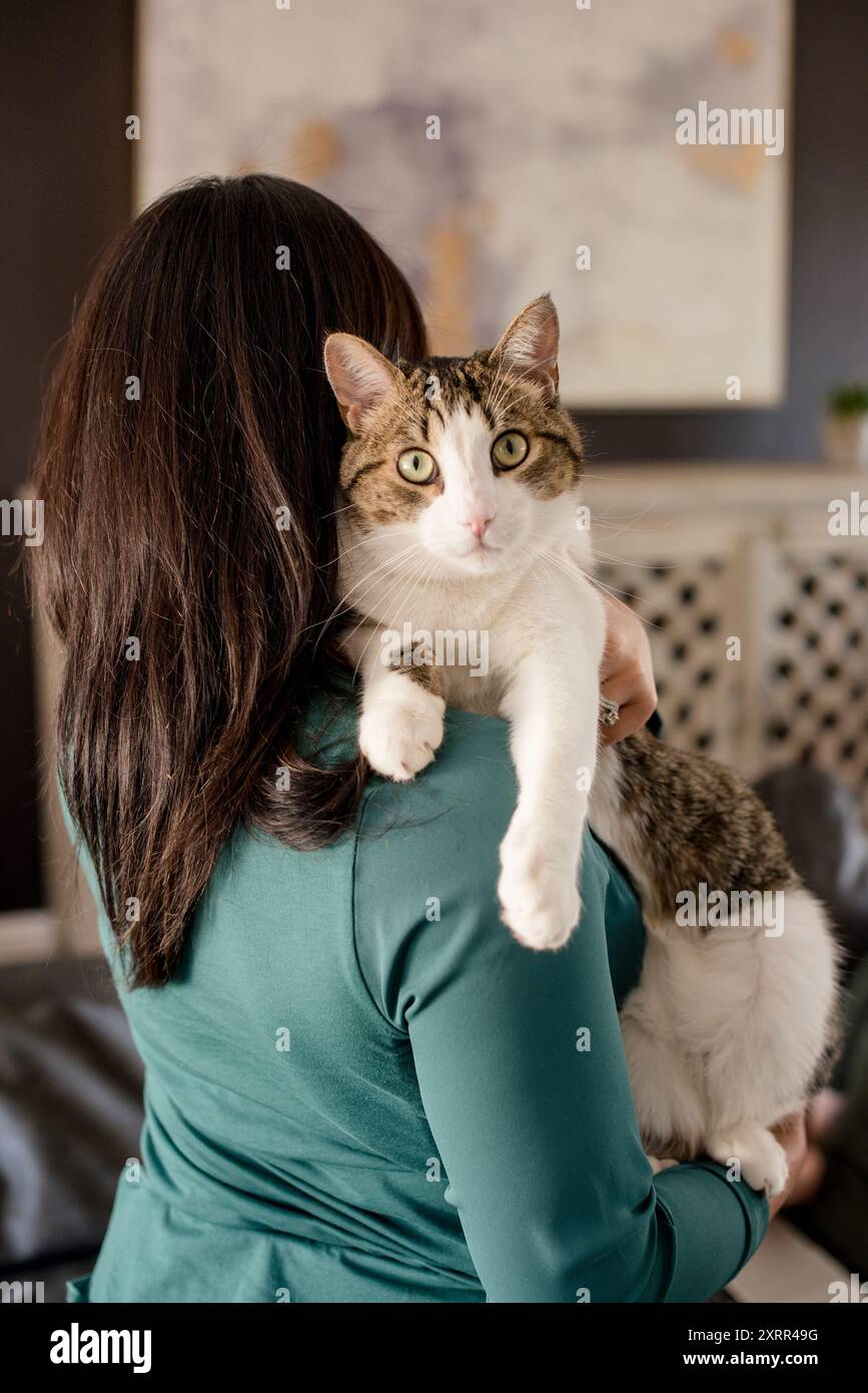 Eine Frau, die die Katze hält und in die andere Richtung schaut Stockfoto