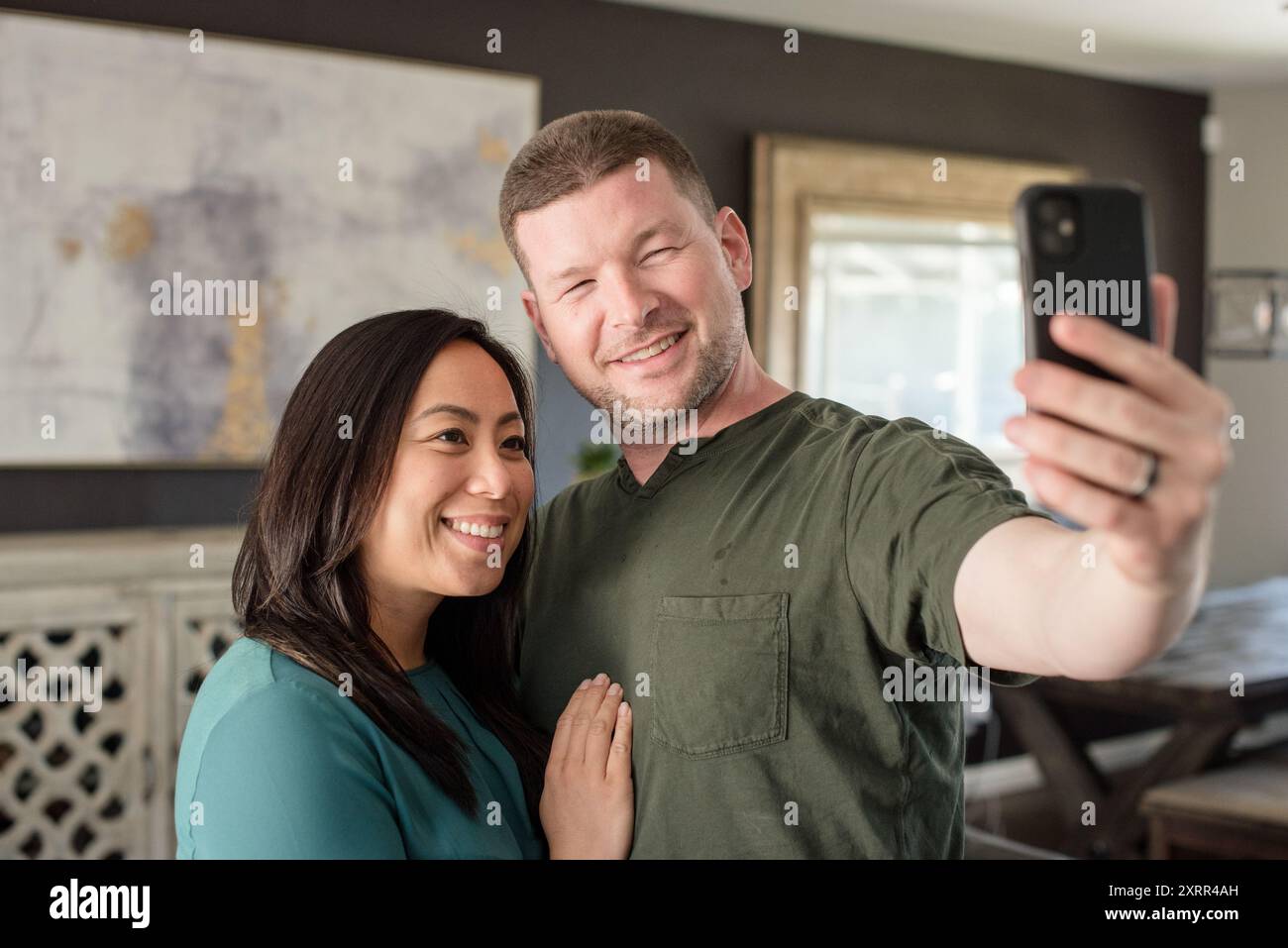 Gemischtes Paar, das zu Hause ein Selfie macht Stockfoto