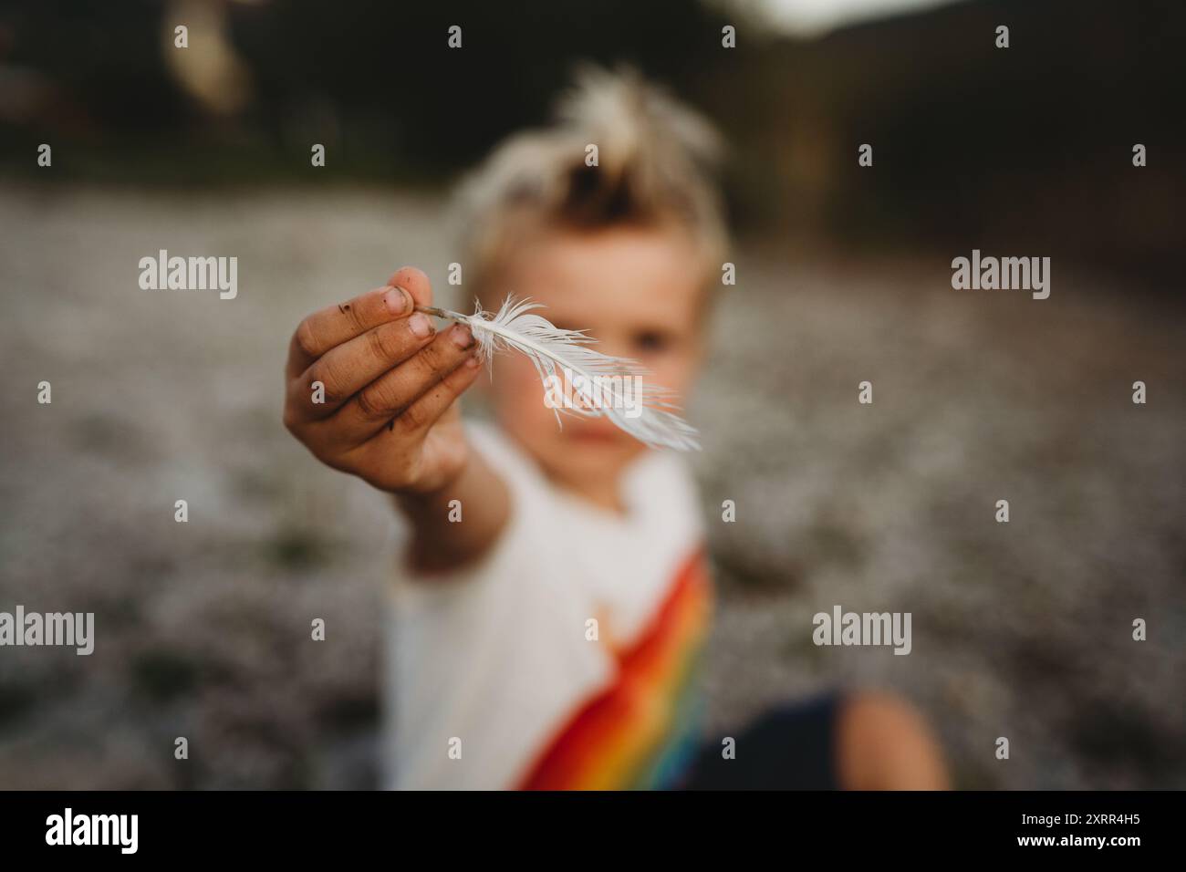 Kleines Kind mit weißer Vogelfeder mit schmutzigen Händen Stockfoto