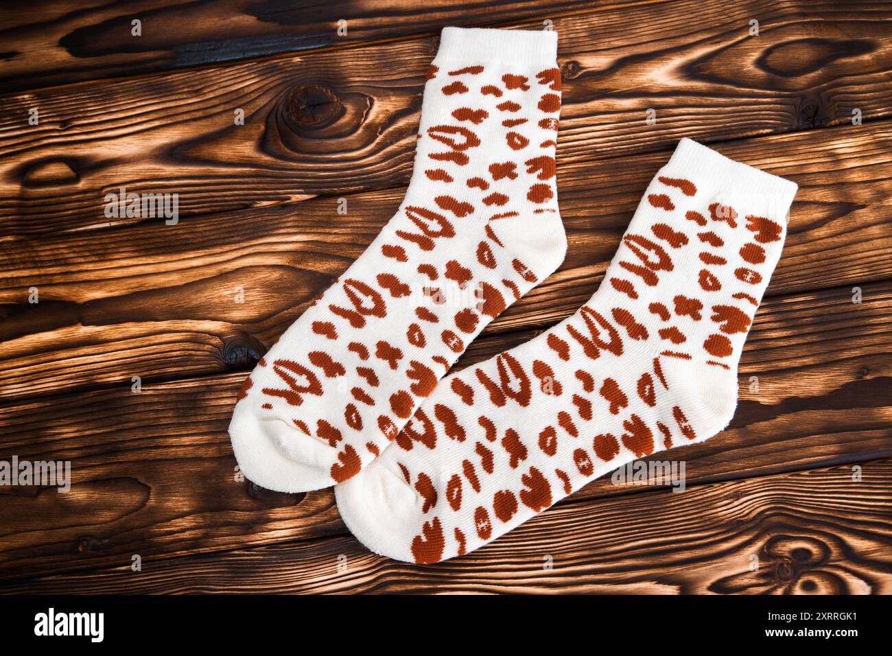 Ein Paar weiße Socken mit markanten braunen Flecken, die auf einer flachen Oberfläche liegen. Stockfoto