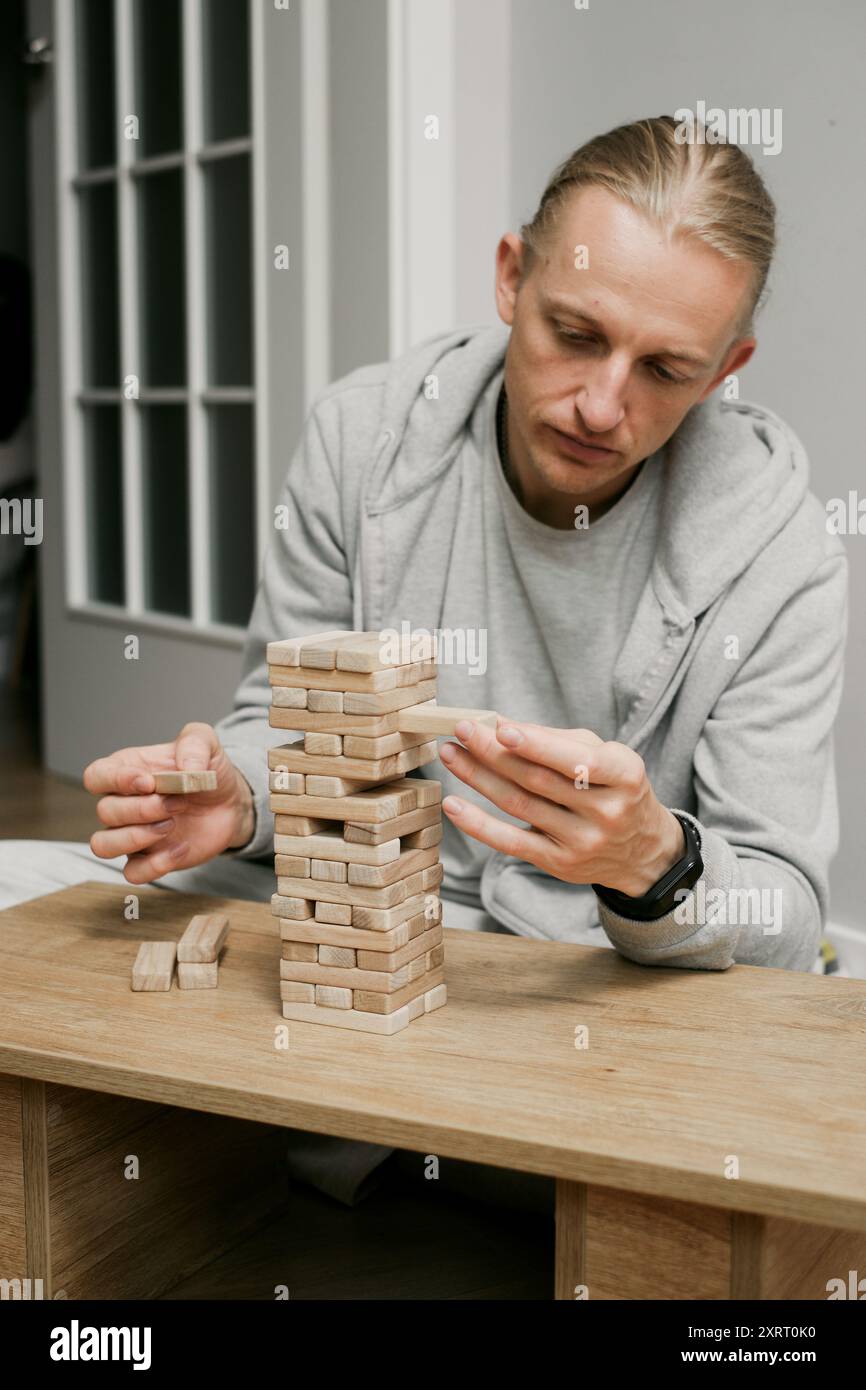 Die Person stapelt sorgfältig Blöcke in Holzturmspiel im Raum zu Hause. Digitale Detox und Konzentration. Qualitätszeit offline Stockfoto