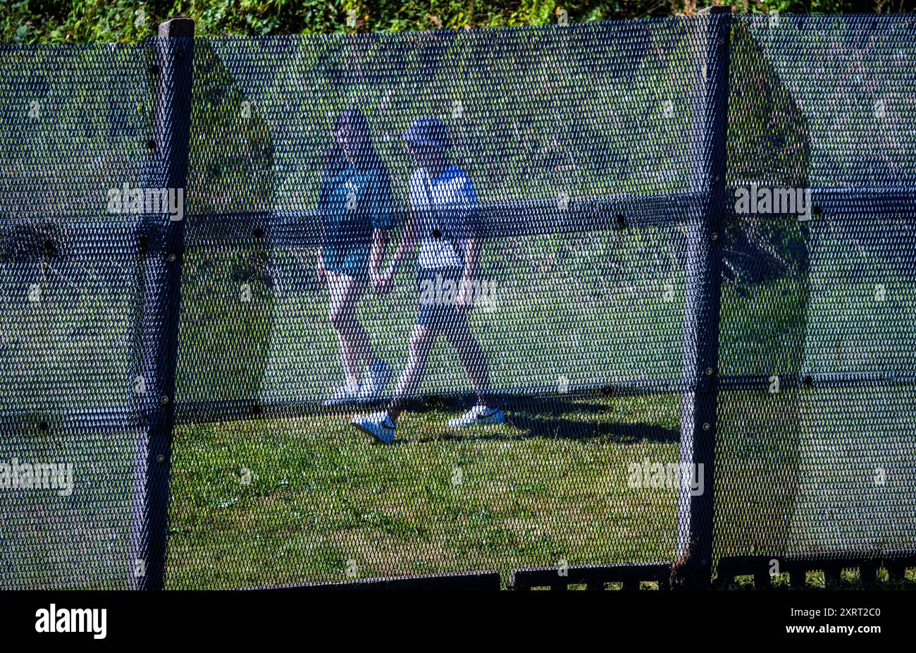 Schlagsdorf, Deutschland. August 2024. Besucher spazieren hinter dem Metallzaun der DDR-Grenztruppen auf dem Gelände des Grenzhus Schlagsdorf. Zahlreiche Veranstaltungen erinnern an den Tag des Mauerbaus und der Schließung der innerdeutschen Grenze am 13. August 1961. Historiker schätzen, dass an der innerdeutschen Grenze rund 650 Menschen ums Leben kamen. Quelle: Jens Büttner/dpa/Alamy Live News Stockfoto