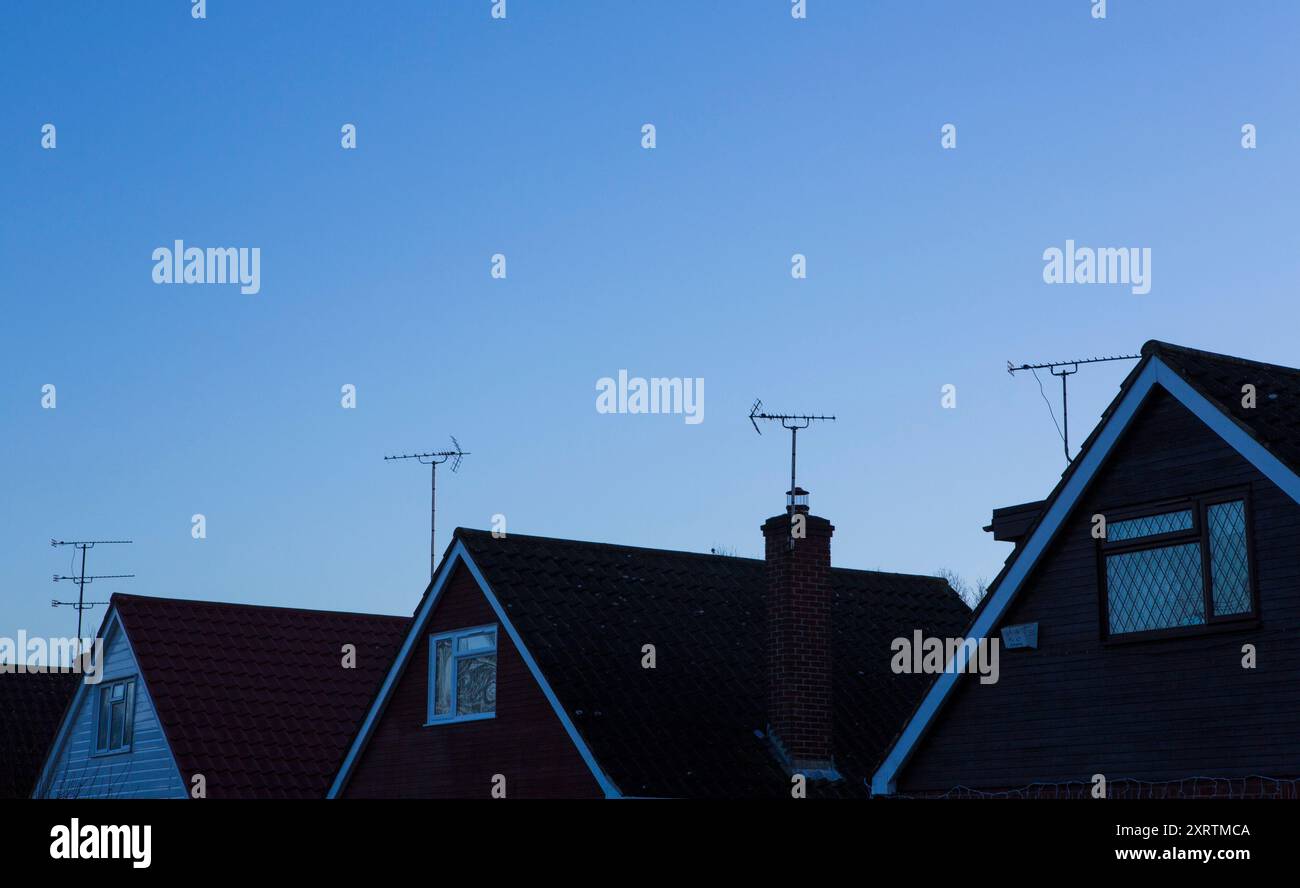 Fernsehantennen auf der Oberseite eine Reihe von Häusern in der Dämmerung. Stockfoto