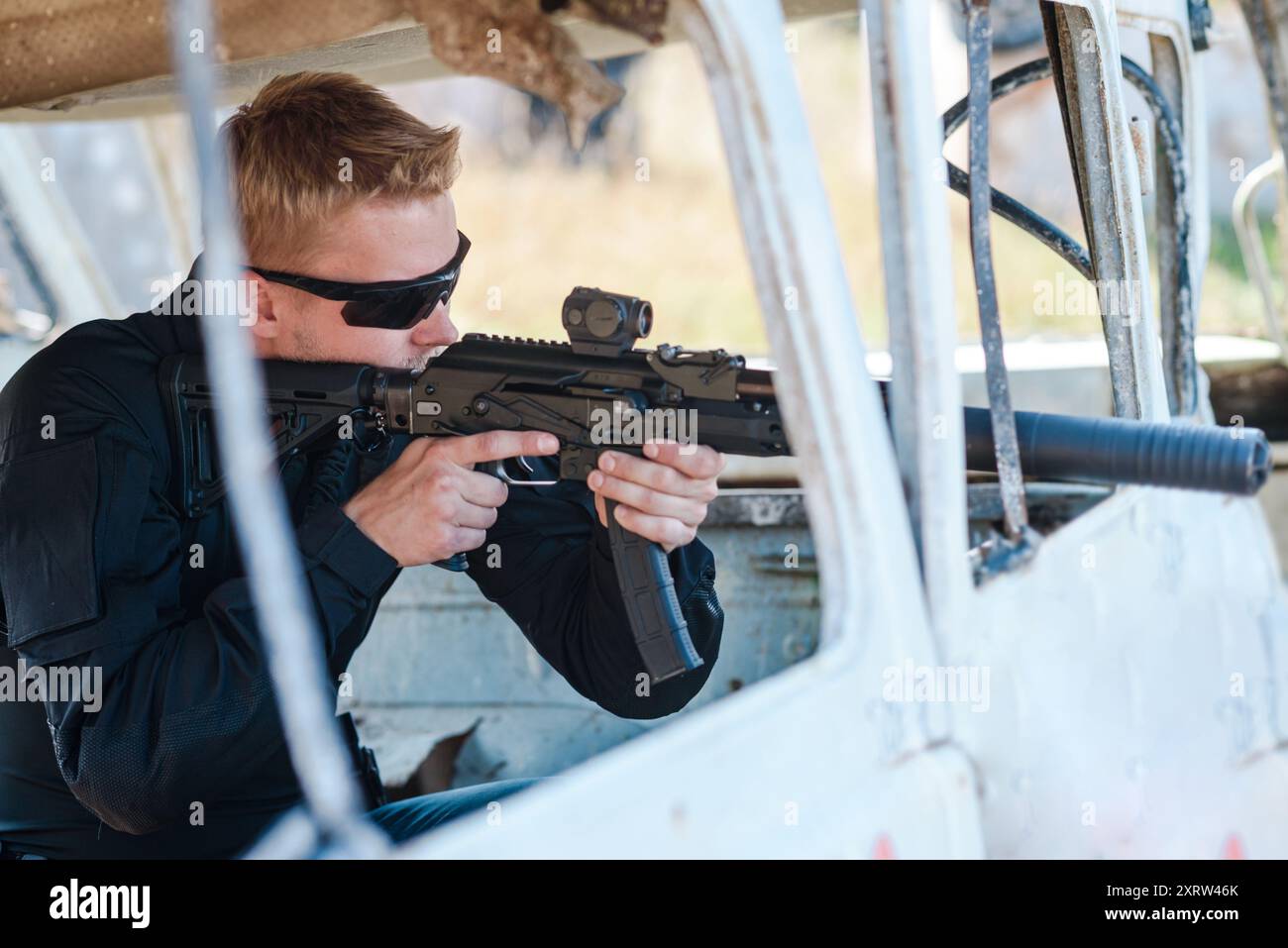 Ein Mann mit einem Maschinengewehr lernt an einem sonnigen Tag auf einem Schießstand zu schießen Stockfoto