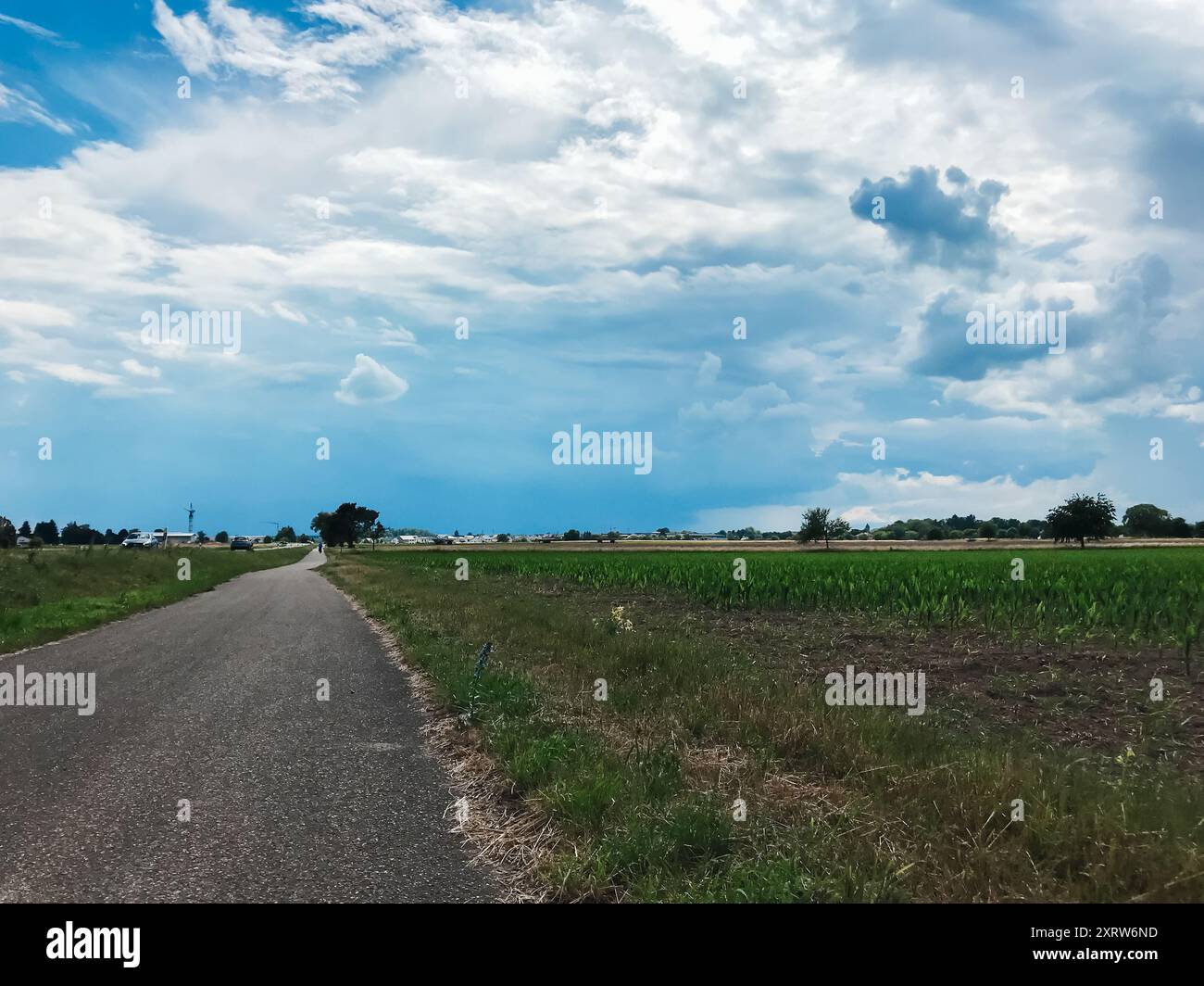 Eine Straße mit bewölktem Himmel im Hintergrund. Der Himmel ist meist bewölkt mit ein paar blauen Flecken Stockfoto